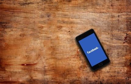 Facebook on a phone on a wooden table