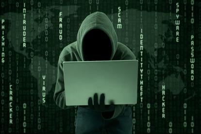 a faceless hacker holding a laptop in a hoodie against a background of 1s and 0s along with cyber threat teams - scam, fraud, virus, identity theft, hacker