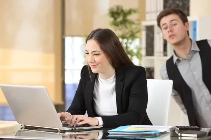 professional male looking at his female coworkers laptop screen 
