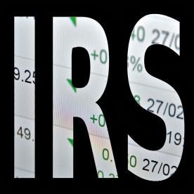 IRS Internal Revenue Service in block letters with stock symbols in the background